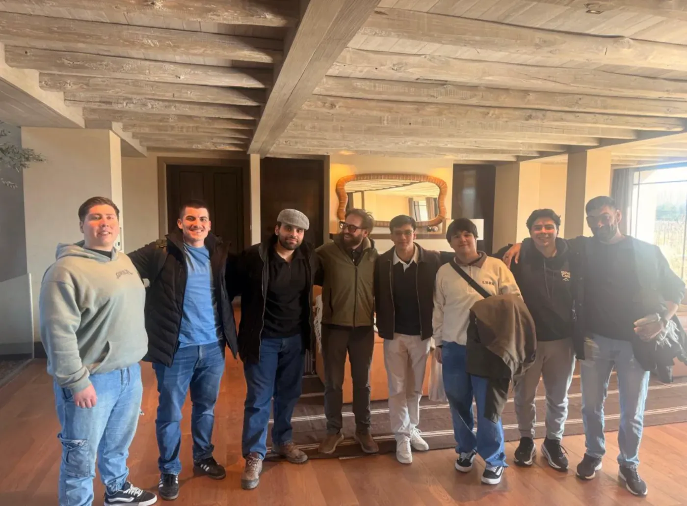 Eight members of the Vantegrate team arm in arm in a room with a beamed ceiling